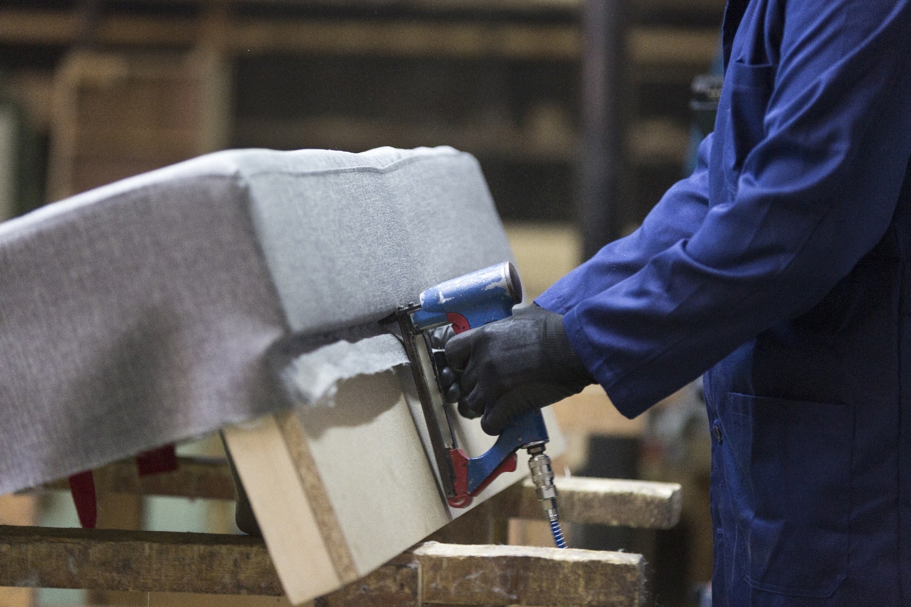 man stapling upholstery and batting to wood chair frame