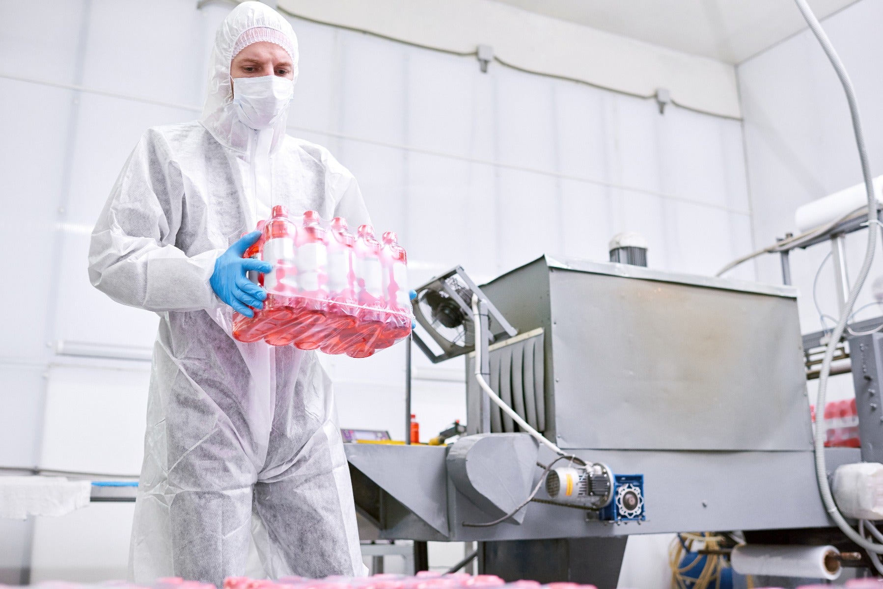 worker removes shrink wrapped bottles from automatic shrink wrap machine