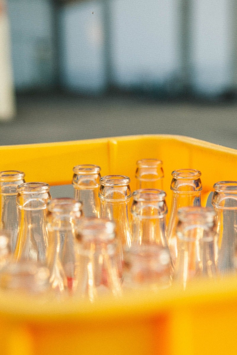 glass bottles in plastic yellow tote container from top view