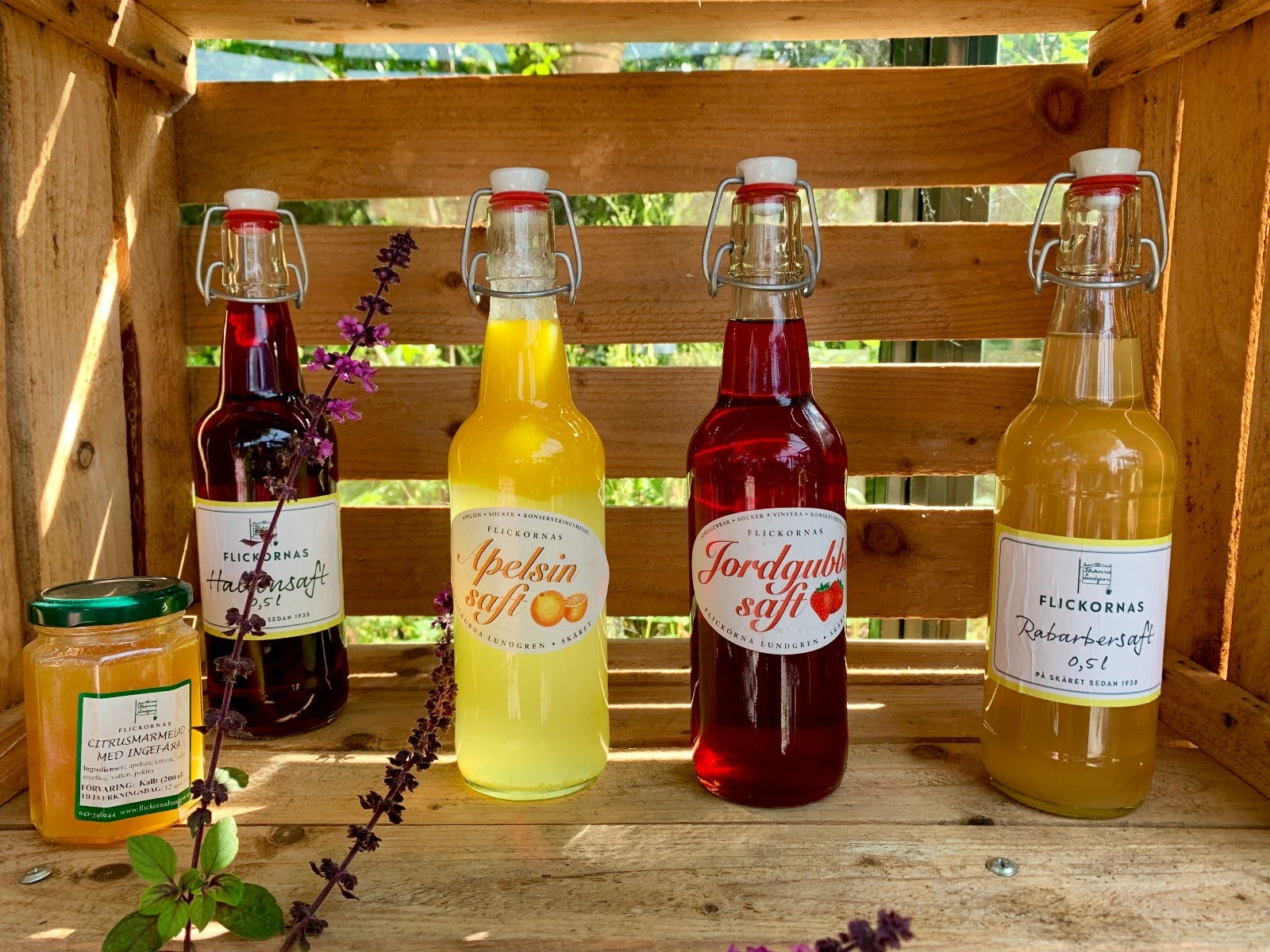 four glass wine bottles and one glass jam jar in wooden crate