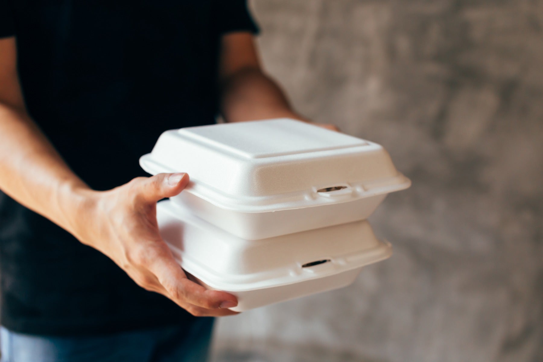 man in black t-shirt holding two stacked foam takeout containers