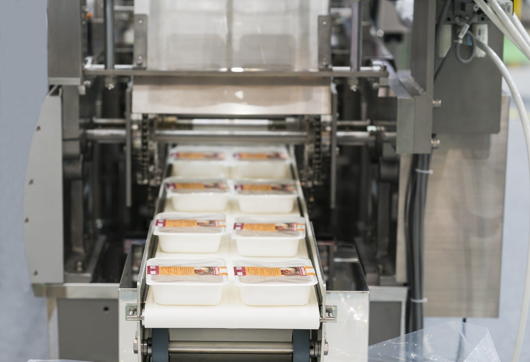 prepackaged meats on conveyor line heading into shrink wrap machine