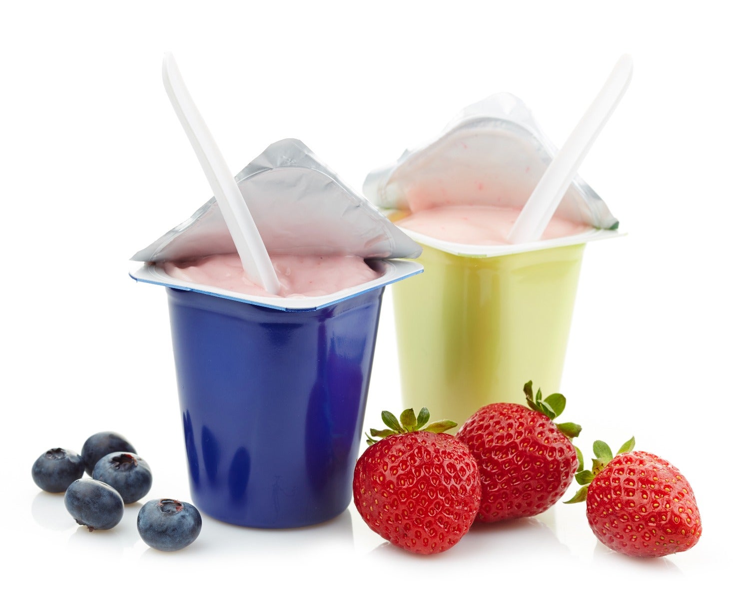 two open lidding films on yogurt cups with blueberries and strawberries on sides