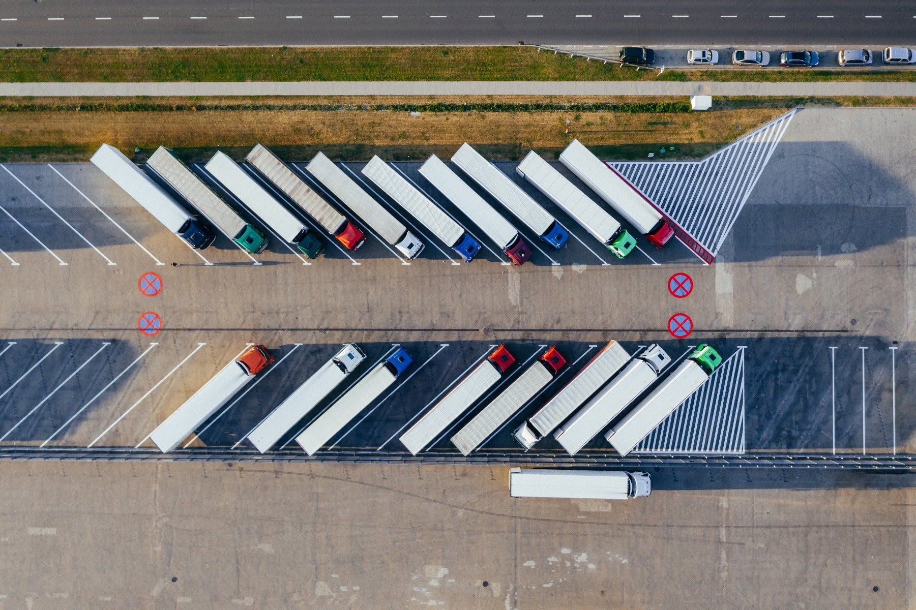 overhead image of semi truck trailers parked at angles back to back in parking lot