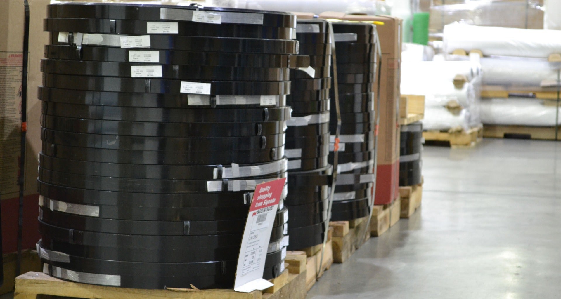 three coils of steel strapping sitting on pallets in warehouse