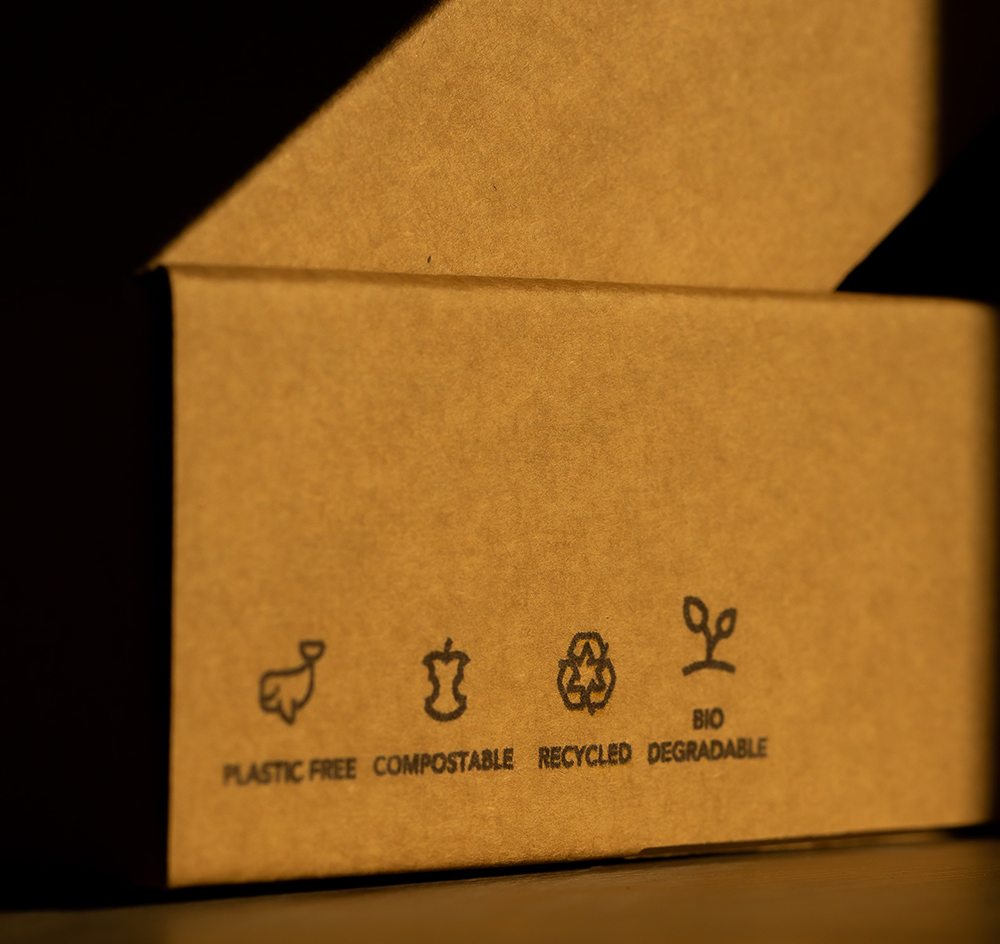 corrugated box on table with sustainable packaging stamps like plastic free and compostable