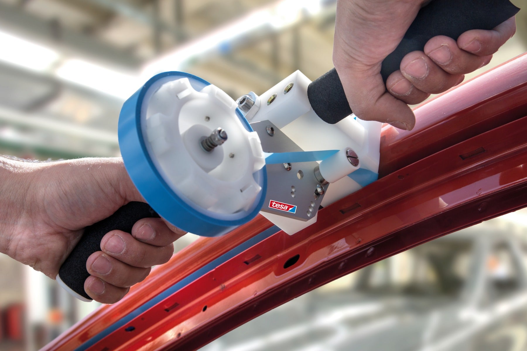 blue tesa automotive tape on roller being applied to inside of red car door